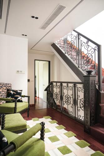 a living room with a staircase and green furniture at A detached, old Shanghai villa on Huaihai Middle Road in Shanghai