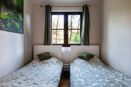 two beds in a room with a window at Kőszikla Vendégház a csendes pihenésre vágyóknak! in Kismaros