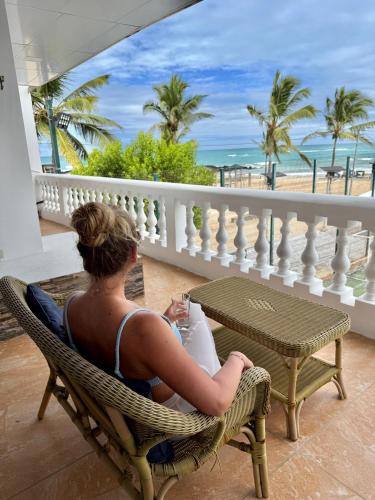 a man sitting in a chair looking out at the beach at Hotel Albemarle Galapagos Beachfront in Puerto Villamil