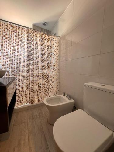 a white bathroom with a toilet and a shower at Urbanstay in Villa Constitución