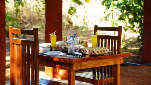 a wooden table with food on it with two chairs at Jungle Crown Cabin in Sigiriya