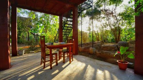 a porch with a table and a chair on a deck at Jungle Crown Cabin in Sigiriya
