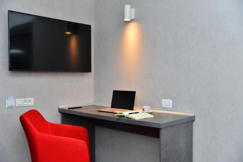 a desk with a laptop and a red chair at ibis Styles Pitesti Arges in Piteşti