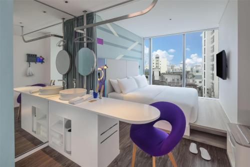 a hotel room with a white bed and a purple chair at Tru by Hilton Nam Dinh City Centre in Nam Ðịnh