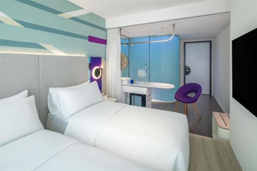 a bedroom with two white beds and a purple chair at Tru by Hilton Da Nang City Centre in Da Nang