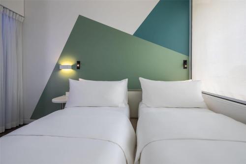 two white beds in a room with a window at Tru by Hilton Da Nang City Centre in Da Nang