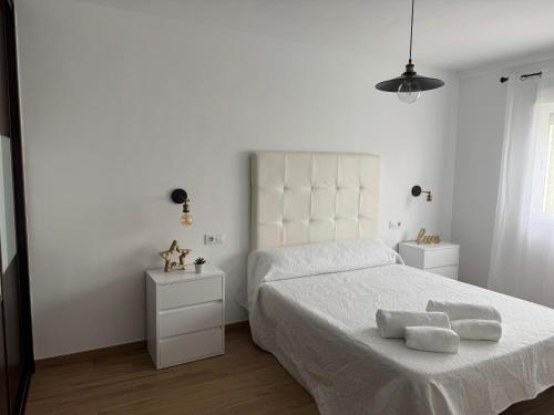 een witte slaapkamer met een bed met twee handdoeken erop bij Alojamiento Carioca in Almodóvar del Río