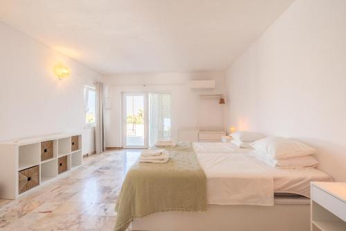 a white bedroom with a large bed with white sheets and pillows at Casa Dos Amigos in Budens