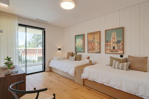 una camera da letto con due letti e una sedia di Cascais Contemporary Villa by Cadenzalux a Cascais