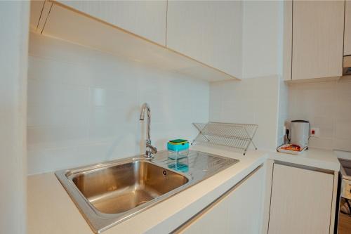 Un fregadero de acero inoxidable en una cocina blanca. en Modern 1BR with Lake View Yas Island Stay for 4, en Abu Dabi
