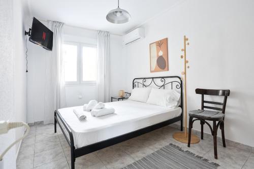 Un dormitorio blanco con una cama y una silla. en Minimal Apt in the Heart of the city, en Tesalónica