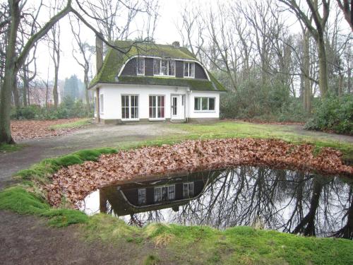 a house with a reflection in a body of water at Westmalle Forest Garden Home in Zoersel