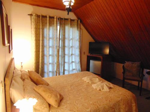 a bedroom with a bed with a window and a television at Pousada Village Por do Sol by Concavus in Campos do Jordão
