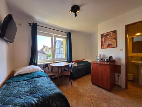 a bedroom with a bed and a table and a window at Willa Mira 200 metrów od morza in Międzyzdroje