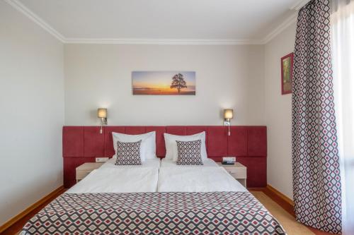 a bedroom with a large bed with a red headboard at Szalajka Liget Hotel és Apartmanházak in Szilvásvárad