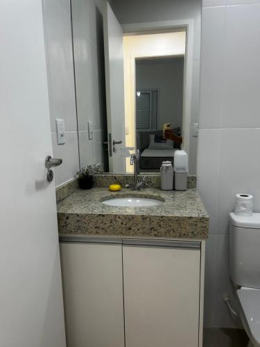 a bathroom with a sink and a toilet and a mirror at APARTAMENTO NA PRAIA CENTRO De BERTIOGA in Bertioga