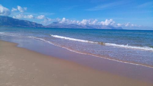 a beach with the ocean and mountains in the background at West Sicily Beach in Balestrate