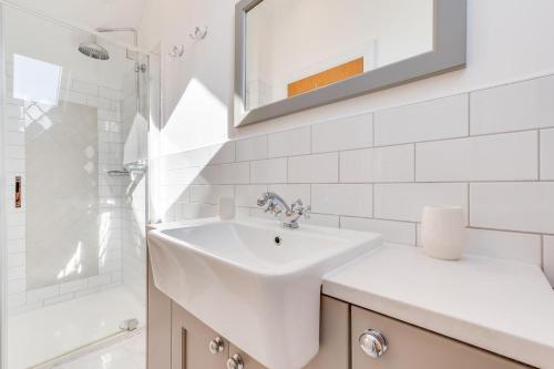 une salle de bain blanche avec un lavabo et un miroir dans l'établissement 3 Bed in Mumbles oc-hh386, à Mumbles