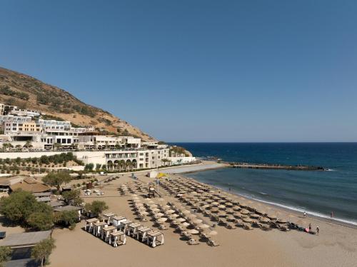 a beach with chairs and umbrellas and the ocean at Fodele Beach Water Park Resort in Fodele