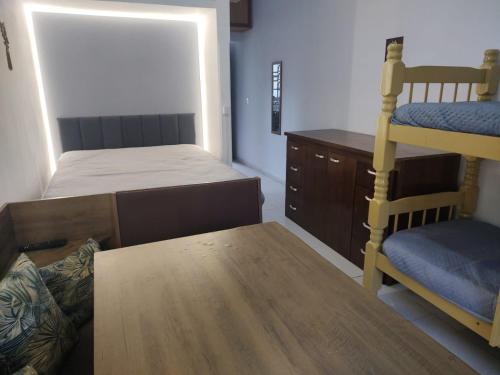 a bedroom with a bunk bed and a desk at Kitnet Sossego na Praia (Caraguatatuba/Massaguaçu) in Caraguatatuba