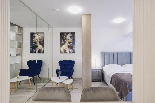 a bedroom with a bed and two blue chairs at Unique by UpTown Apartments in Iaşi