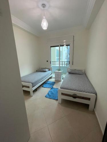 two beds in a room with a window at Casa residence Khair in Tangier