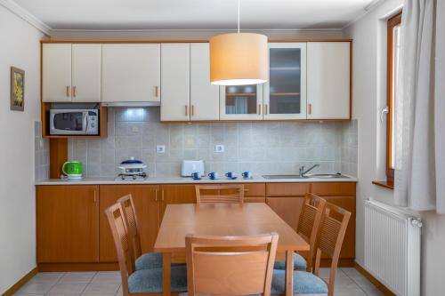 a kitchen with a wooden table and chairs at Szalajka Liget Hotel és Apartmanházak in Szilvásvárad