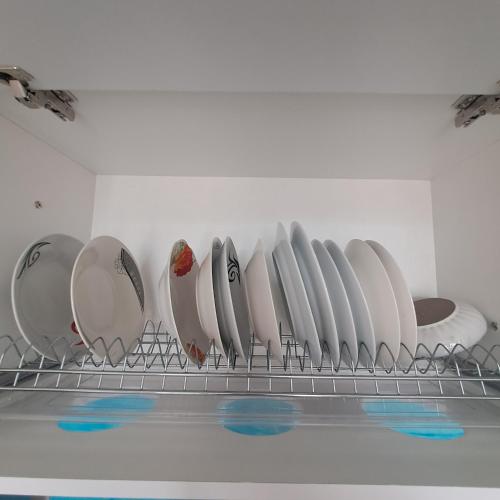 a row of white plates on a shelf at Noli's Apartment in Shëngjin