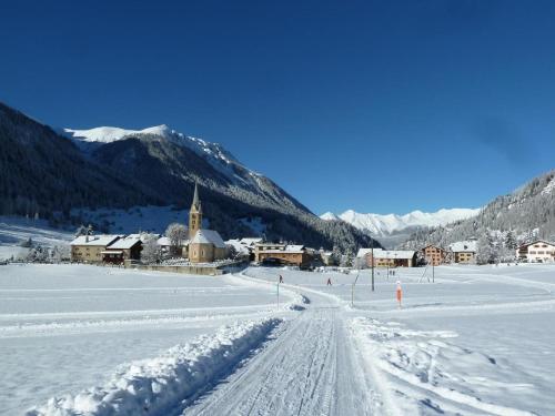 a snow covered village with a church in the distance at Bijou Biobergün in Bergün