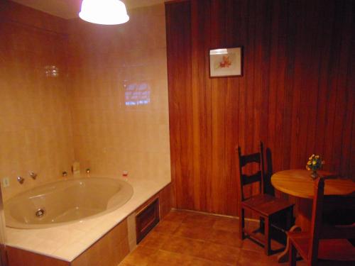 a bathroom with a tub and a table with a chair at Pousada Village Por do Sol by Concavus in Campos do Jordão