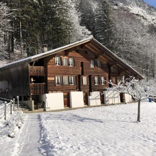 a log cabin with snow on the ground in front at Brachli in Innertkirchen