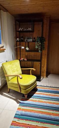 a yellow chair in a room with a rug at Brachli in Innertkirchen