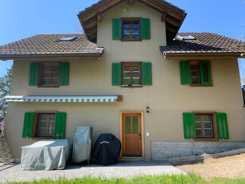 a house with green shutters and a table in front of it at Thal in Vitznau