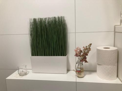 a white shelf with a vase of green grass at Gemütliche Parterre Ferienwohnung Mit Terrasse in Ohmstal