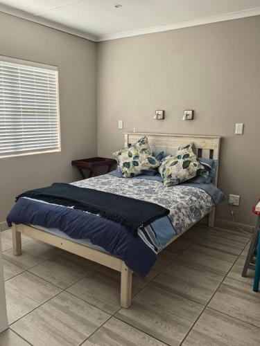 a bedroom with a bed with blue sheets and pillows at The Pearl in Pearly Beach
