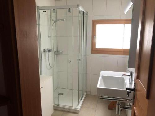 a bathroom with a glass shower and a sink at Chesa Muntanella in Sils Maria