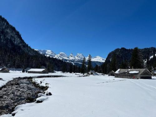 a field covered in snow with houses and mountains at Chäserruggblick in Unterwasser