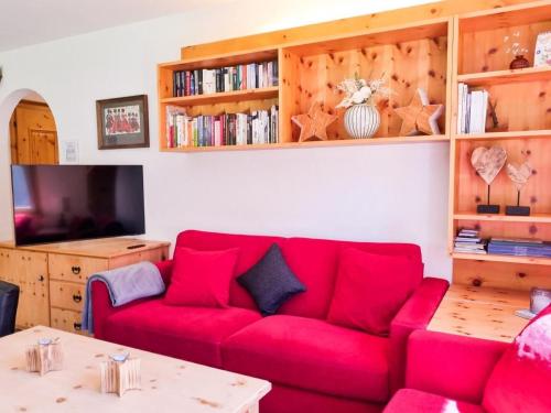 a living room with a red couch and a tv at Curtins16 in Pontresina