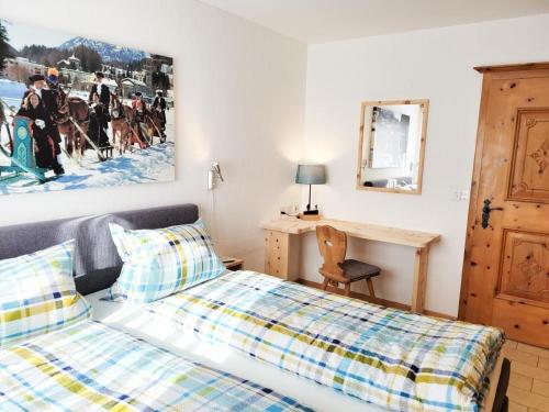 a bedroom with a bed and a desk with a picture on the wall at Curtins16 in Pontresina