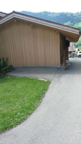 a building with a driveway next to a house at Mannried 2 1 2 Zimmerwohnung Rustikal in Zweisimmen