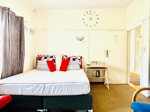 a bedroom with a bed with red pillows and a clock at Executive Accommodation Bellville 1 in Bellville