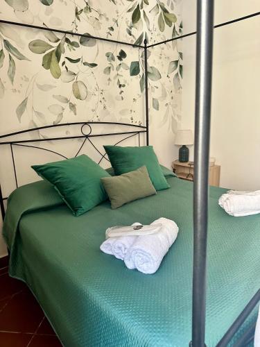 a bed with a green comforter with towels on it at VerdeNera in Terni