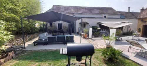 a patio with a black umbrella and a grill at GITE HARY in Villeblevin