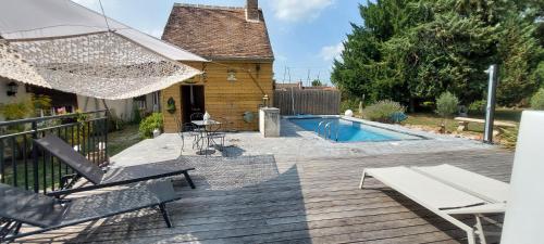 a wooden deck with chairs and a swimming pool at GITE HARY in Villeblevin
