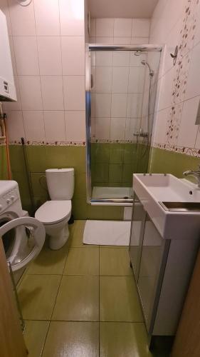 a bathroom with a toilet and a sink and a shower at Apartament Zielony Ogród Ząbki in Ząbki