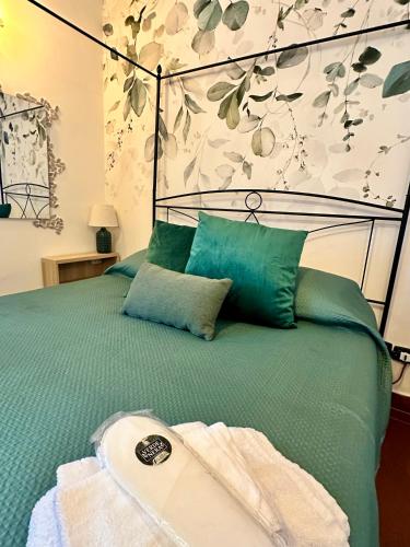 a bed with a green comforter with a towel on it at VerdeNera in Terni