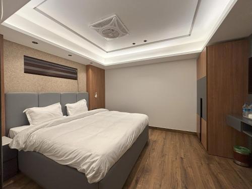 a bedroom with a large bed with white sheets at Plaza 14 in Jammu
