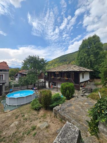 a backyard with a house and a swimming pool at Къща за гости Хитър Петър in Apriltsi
