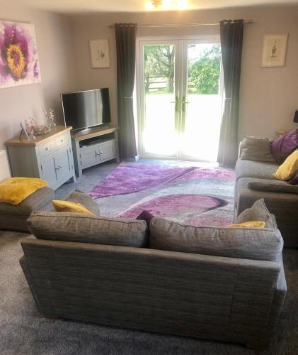 a living room with a couch and a tv at 2 bedroom bungalow, 15 minutes to Alton Towers, dog friendly in Wetleyrocks