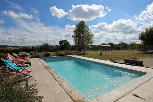 a swimming pool with two chairs and a yard at Fonbanoux in Flavignac